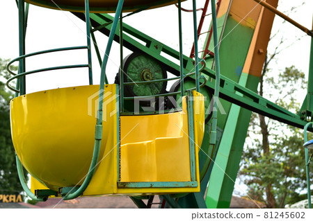 Cradle yellow amusement ride Ferris wheel without people in the city park. Cradle yellow amusement ride Ferris wheel without people in the city park. 81245602
