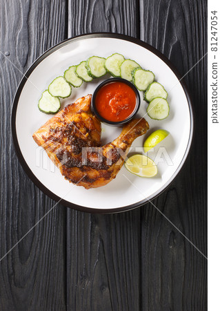 Ayam Bakar is a dish of charcoal-grilled chicken marinated in kecap manis, coconut oil, shallot, garlic, chilli pepper, coriander, tamarind juice, candlenut, turmeric and galangal. Vertical top view Ayam Bakar is a dish of charcoal-grilled chicken marinated in kecap manis, coconut oil, shallot, garlic, chilli pepper, coriander, tamarind juice, candlenut, turmeric and galangal. Vertical top view 81247054