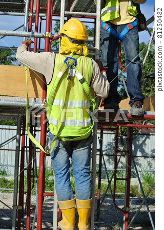 MALACCA, MALAYSIA -JULY 23, 2016: Construction workers wearing safety harness belt at other safety gear during working at the construction site area. MALACCA, MALAYSIA -JULY 23, 2016: Construction workers wearing safety harness belt at other safety gear during working at the construction site area. 81250482
