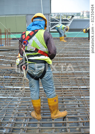 MALACCA, MALAYSIA -JULY 23, 2016: Construction workers wearing safety harness belt at other safety gear during working at the construction site area. MALACCA, MALAYSIA -JULY 23, 2016: Construction workers wearing safety harness belt at other safety gear during working at the construction site area. 81250484