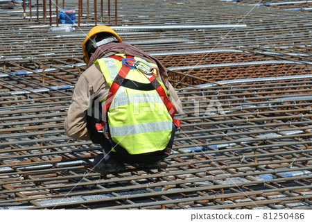 MALACCA, MALAYSIA -JULY 23, 2016: Construction workers wearing safety harness belt at other safety gear during working at the construction site area. MALACCA, MALAYSIA -JULY 23, 2016: Construction workers wearing safety harness belt at other safety gear during working at the construction site area. 81250486
