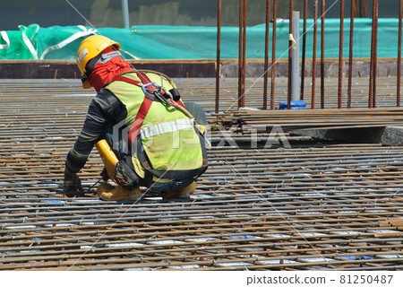 MALACCA, MALAYSIA -JULY 23, 2016: Construction workers wearing safety harness belt at other safety gear during working at the construction site area. MALACCA, MALAYSIA -JULY 23, 2016: Construction workers wearing safety harness belt at other safety gear during working at the construction site area. 81250487