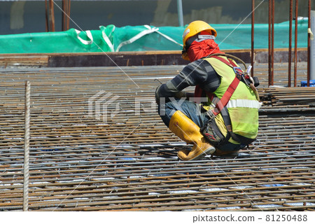 MALACCA, MALAYSIA -JULY 23, 2016: Construction workers wearing safety harness belt at other safety gear during working at the construction site area. MALACCA, MALAYSIA -JULY 23, 2016: Construction workers wearing safety harness belt at other safety gear during working at the construction site area. 81250488