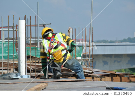 MALACCA, MALAYSIA -JULY 23, 2016: Construction workers wearing safety harness belt at other safety gear during working at the construction site area. MALACCA, MALAYSIA -JULY 23, 2016: Construction workers wearing safety harness belt at other safety gear during working at the construction site area. 81250490