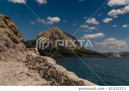 The Republic of Crimea. July 15, 2021. Picturesque view in sunny weather of Mount Sokol in the village of Novy Svet from the side of the Golitsyn trail through Zelenaya Bay. The Republic of Crimea. July 15, 2021. Picturesque view in sunny weather of Mount Sokol in the village of Novy Svet from the side of the Golitsyn trail through Zelenaya Bay. 81252521