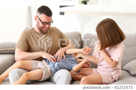 Positive happy family of three enjoying carefree time together at home, dad playing with kids Positive happy family of three enjoying carefree time together at home, dad playing with kids 81252573