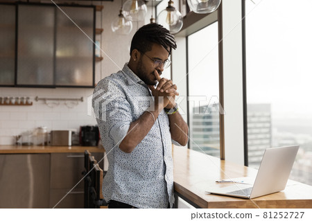 Pensive African guy looks at laptop pondering over problem solution Pensive African guy looks at laptop pondering over problem solution 81252727