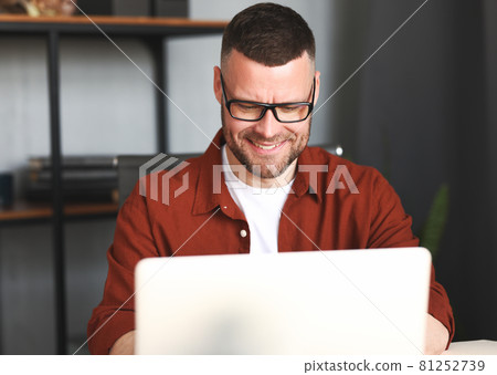 Happy male freelancer working on laptop computer remotely at home Happy male freelancer working on laptop computer remotely at home 81252739