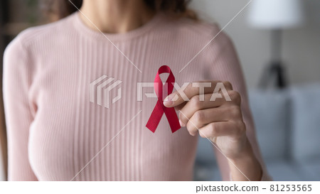 Close up female volunteer holding red ribbon in hands Close up female volunteer holding red ribbon in hands 81253565