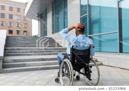 Irritated impaired black man in wheelchair having no possibility to enter building without ramp, outdoors 81253966