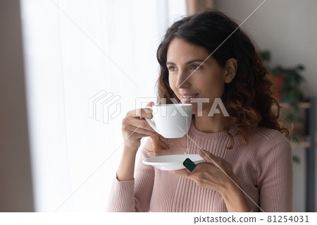 Smiling woman standing indoor with cup of tea 81254031