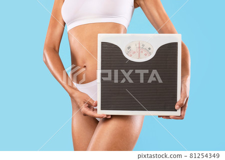 Lady Holding Bathroom Scales Isolated On Blue Studio Wall 81254349