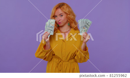 Proud arrogant rich stylish girl holding money cash in dollars banknotes, smiling, looking at camera 81255962