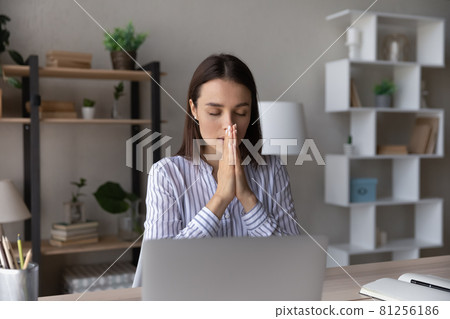 Superstitious young woman worker pray at workplace Superstitious young woman worker pray at workplace 81256186