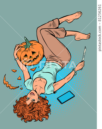 A beautiful woman carves a Halloween pumpkin. The girl is lying on the floor with a knife and a smartphone. Autumn holiday 81256261