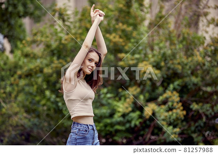 Elegant young woman is dancing in city garden. Elegant young woman is dancing in city garden. 81257988