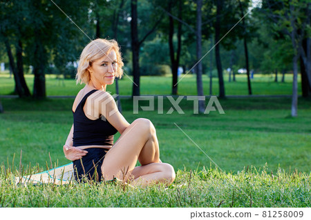 Middle aged woman makes exercises of yoga outdoors. Middle aged woman makes exercises of yoga outdoors. 81258009