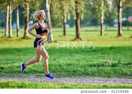 Slim woman in sportswear runs in park. Slim woman in sportswear runs in park. 81258486