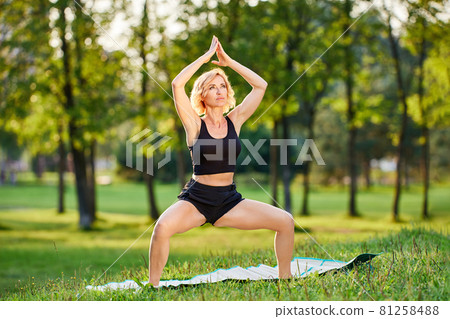 Woman in sportswear makes yoga training outside. Woman in sportswear makes yoga training outside. 81258488