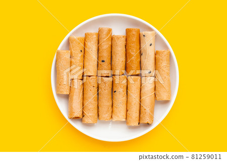 Thai crispy coconut rolls in white plate on yellow background. Thai crispy coconut rolls in white plate on yellow background. 81259011