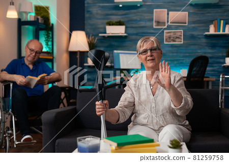 Elder husband and wife with crutches and wheelchair 81259758