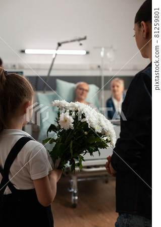 Caring granddaughter bringing flowers gift to sick old grandfather 81259801
