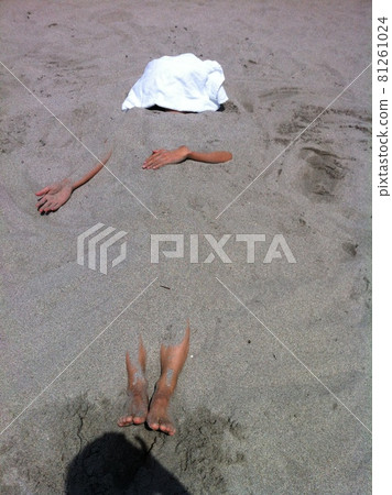 A man buried in a sandy beach A man buried in a sandy beach 81261024