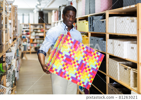 Smiling african american man choosing storage box at store Smiling african american man choosing storage box at store 81263021