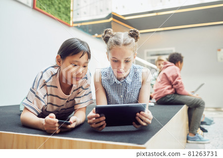Two Girls Using Gadgets in School 81263731