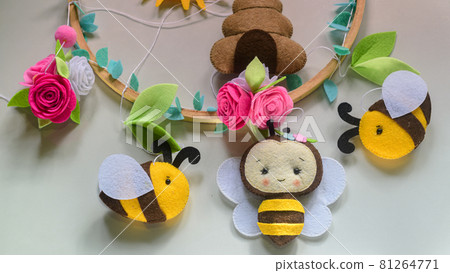 Beautiful cot mobile laid out on a tiled floor, stuffed cute bees and flowers attached to the embroidery hoop cot mobile. Beautiful cot mobile laid out on a tiled floor, stuffed cute bees and flowers attached to the embroidery hoop cot mobile. 81264771