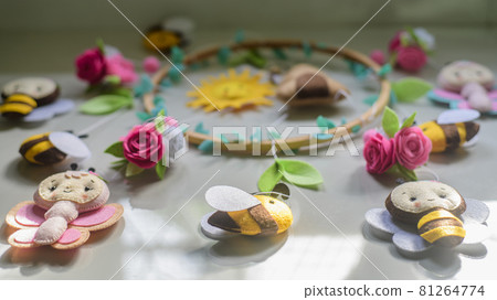 Beautiful cot mobile laid out on a tiled floor, stuffed cute bees and flowers attached to the embroidery hoop cot mobile. Beautiful cot mobile laid out on a tiled floor, stuffed cute bees and flowers attached to the embroidery hoop cot mobile. 81264774