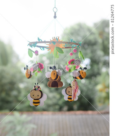 Bees and beehive-themed beautiful baby crib mobile hanging. Plush and cute bees with flowers and leaves. Felt cot mobile close up. Bees and beehive-themed beautiful baby crib mobile hanging. Plush and cute bees with flowers and leaves. Felt cot mobile close up. 81264775