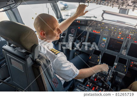 High angle view of professional pilot sitting in an airplane cabin, ready for takeoff 81265719