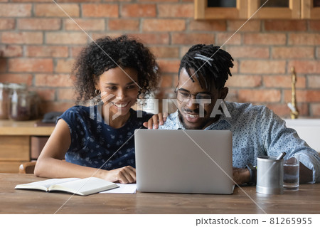 Happy millennial mixed race Black couple browsing internet on laptop 81265955