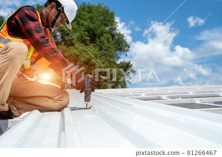 Roofer working at metal profile roof installation,Roofing tools,Electric drill used on new roofs. 81266467