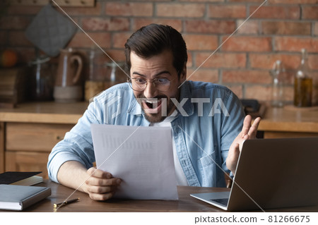 Excited young man triumph with good news in paperwork 81266675