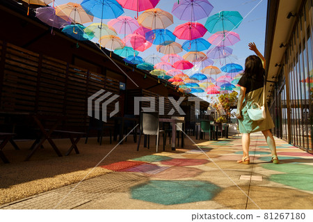A woman in the shadow of many vinyl umbrellas and bright umbrellas that color the blue sky on the terrace of Himi Ichibangai A woman in the shadow of many vinyl umbrellas and bright umbrellas that color the blue sky on the terrace of Himi Ichibangai 81267180