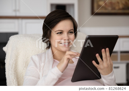 Happy positive young pregnant woman using tablet Happy positive young pregnant woman using tablet 81268624