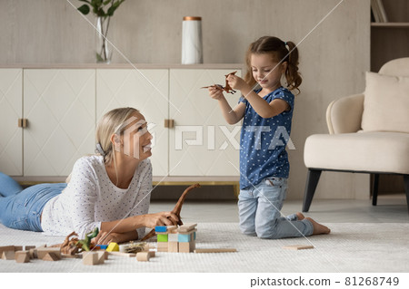 Happy mom and daughter playing with dinosaurs on warm floor, Happy mom and daughter playing with dinosaurs on warm floor, 81268749