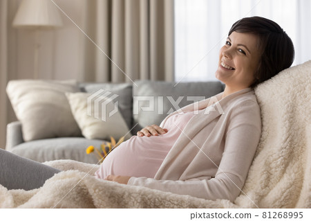 Happy pregnant young woman resting in armchair at home Happy pregnant young woman resting in armchair at home 81268995