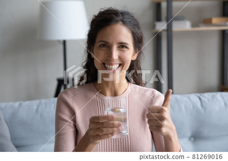 Happy woman holding glass of water showing thumbs up gesture Happy woman holding glass of water showing thumbs up gesture 81269016