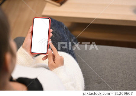 Cropped shot of young woman using mobile phone sending sms or texting while sitting on couch at home. 81269667