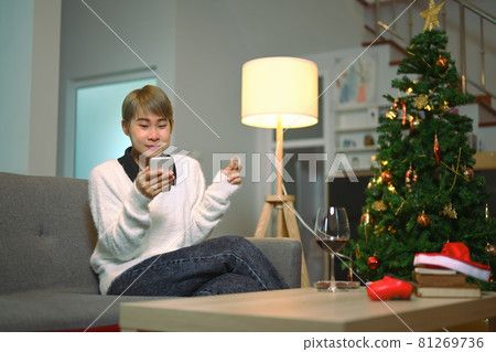 A cheerful woman talking meeting friends on video call celebrating in holiday distance online together on mobile phone at home. 81269736