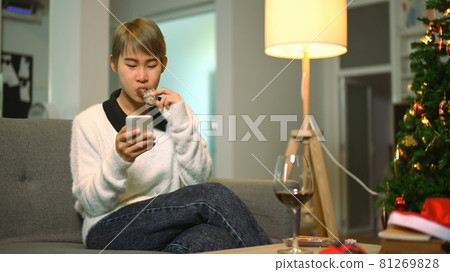 A young woman during quarantine long distance celebration with her friend over smar tphone at home. A young woman during quarantine long distance celebration with her friend over smar tphone at home. 81269828