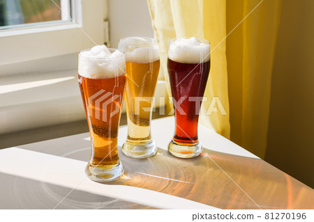 Three glasses with different sorts of beer on table 81270196