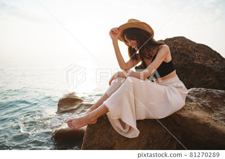 Woman traveler sitting near sea on cliff injoying view of sea and nature Woman traveler sitting near sea on cliff injoying view of sea and nature 81270289