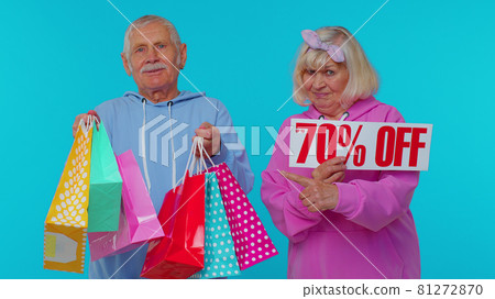 Senior grandparents showing shopping bags and Up To 70 Percent Off banner text, Black Friday holiday Senior grandparents showing shopping bags and Up To 70 Percent Off banner text, Black Friday holiday 81272870