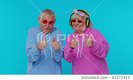 Mature stylish grandparents pensioners listening music via headphones, dancing disco fooling around 81272915