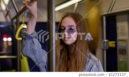 Tired, bored young woman standing alone in bus transport after hard work day and falling asleep 81273137