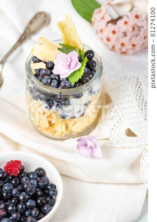 Dessert with fresh blueberries, granola and yogurt on a white linen tablecloth, vertical, close-up 81274100